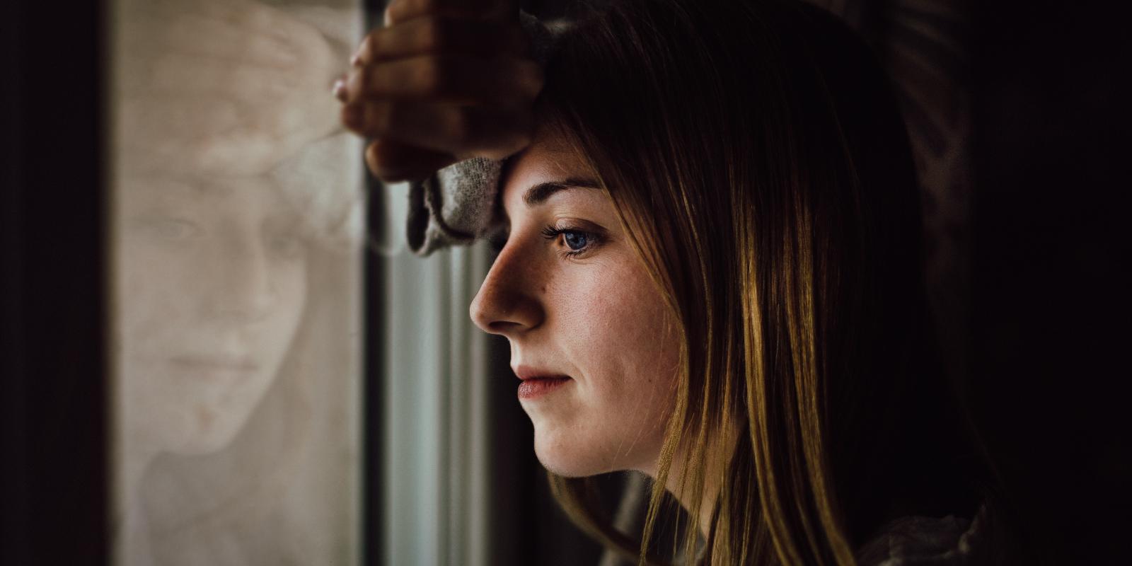 Foto af ung kvinde der kigger ud af et vindue