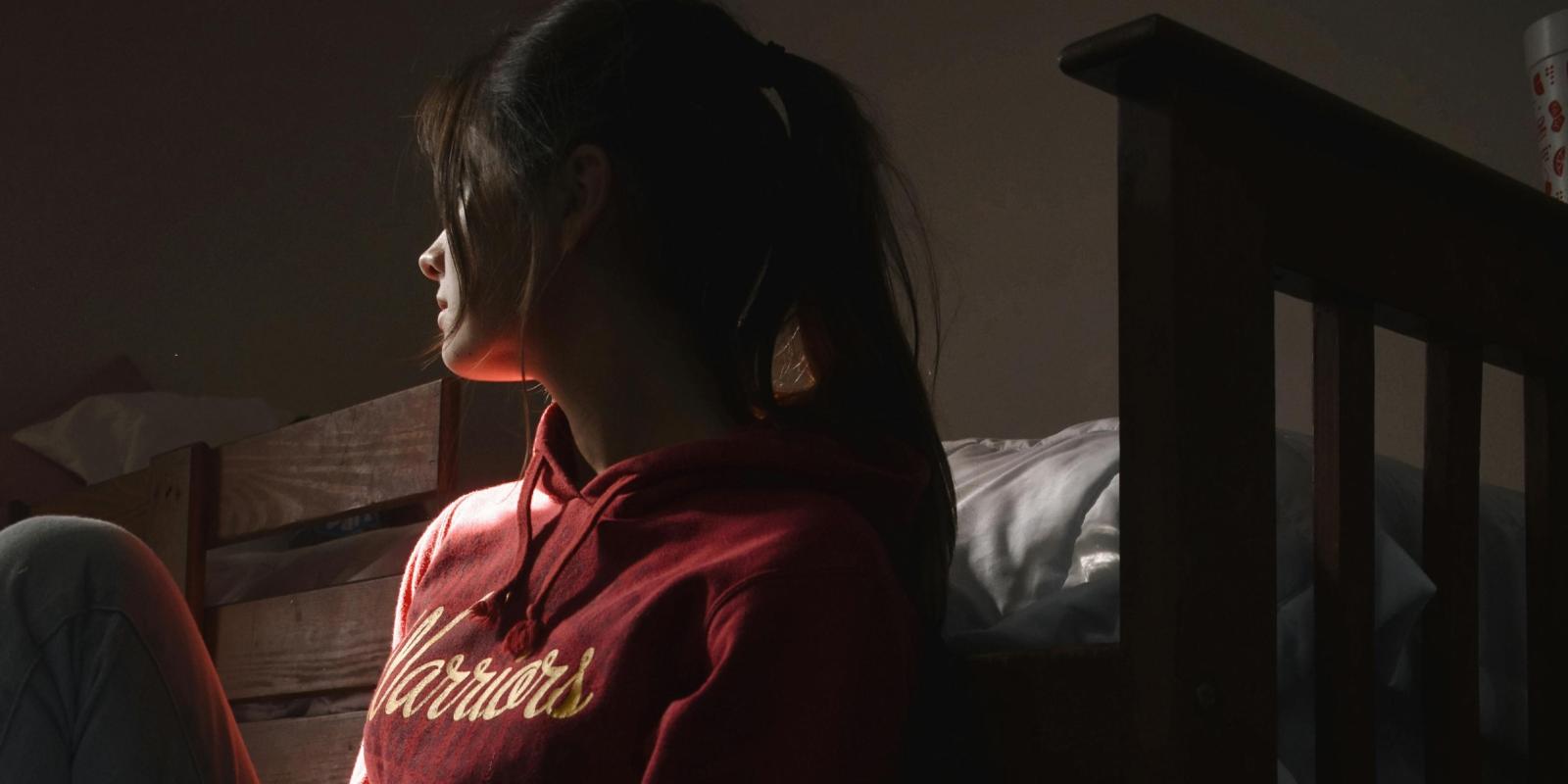 Kvinde sidder op ad seng